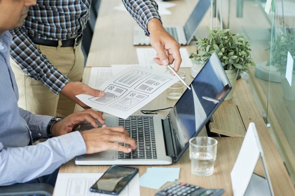 Deux professionnels du web travaillant sur un site internet avec ordinateur portable et documents